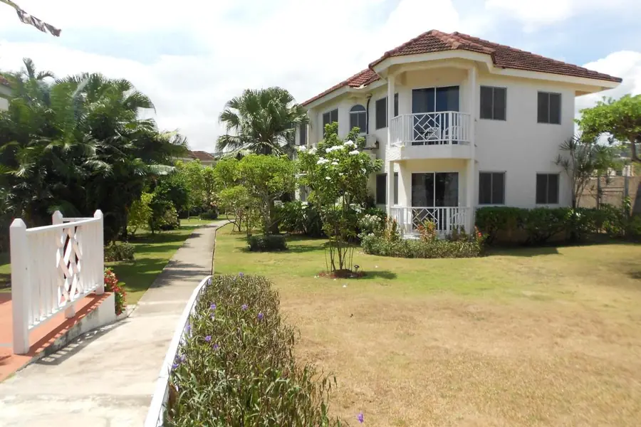 One of the two-storey buildings at Pipers Cove Resort, with balconies, among palm trees and gardens