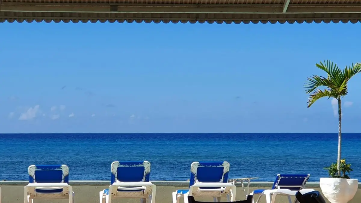 Blue sun loungers and the pool at Pipers Cove Resort, facing the Caribbean Sea